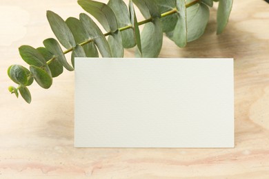 Photo of Blank business card and eucalyptus branch on wooden table, closeup. Mockup for design