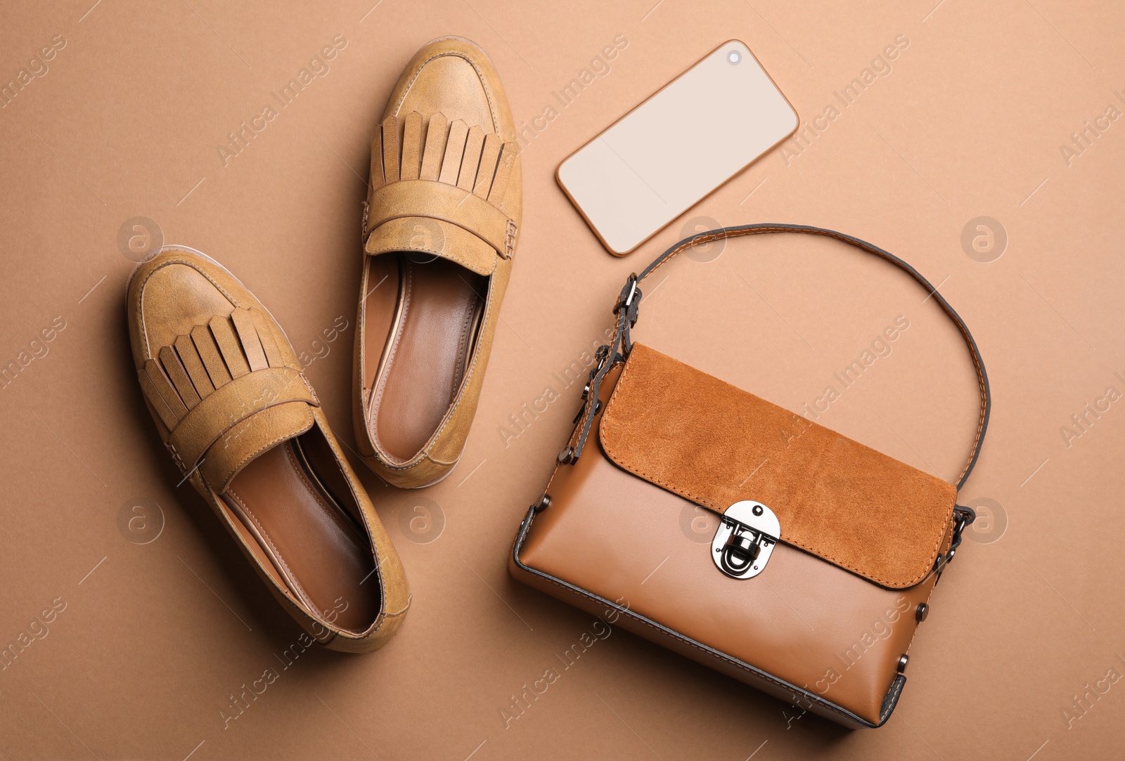 Photo of Stylish shoes, small woman's bag and smartphone on brown background, flat lay