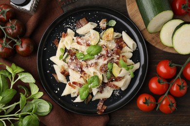 Photo of Tasty pasta with bacon and basil on wooden table, flat lay