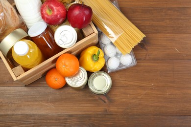 Humanitarian aid. Different food products for donation on wooden table, flat lay. Space for text