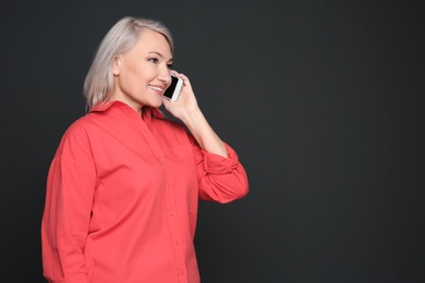 Mature woman talking on mobile phone against black background