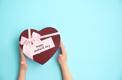 Photo of Child holding gift box for Mother's Day on color background