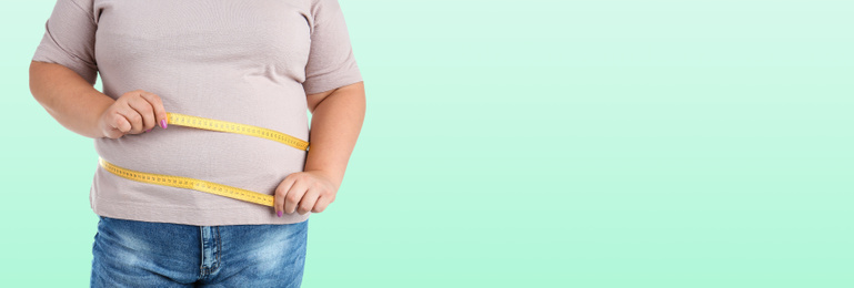 Image of Closeup view of overweight woman with measuring tape on light green background, space for text. Banner design