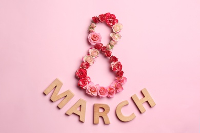 Photo of Phrase "8 March" made of beautiful flowers and wooden letters on color background, top view. Happy Women's Day