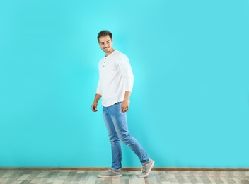 Photo of Young man in stylish jeans near color wall