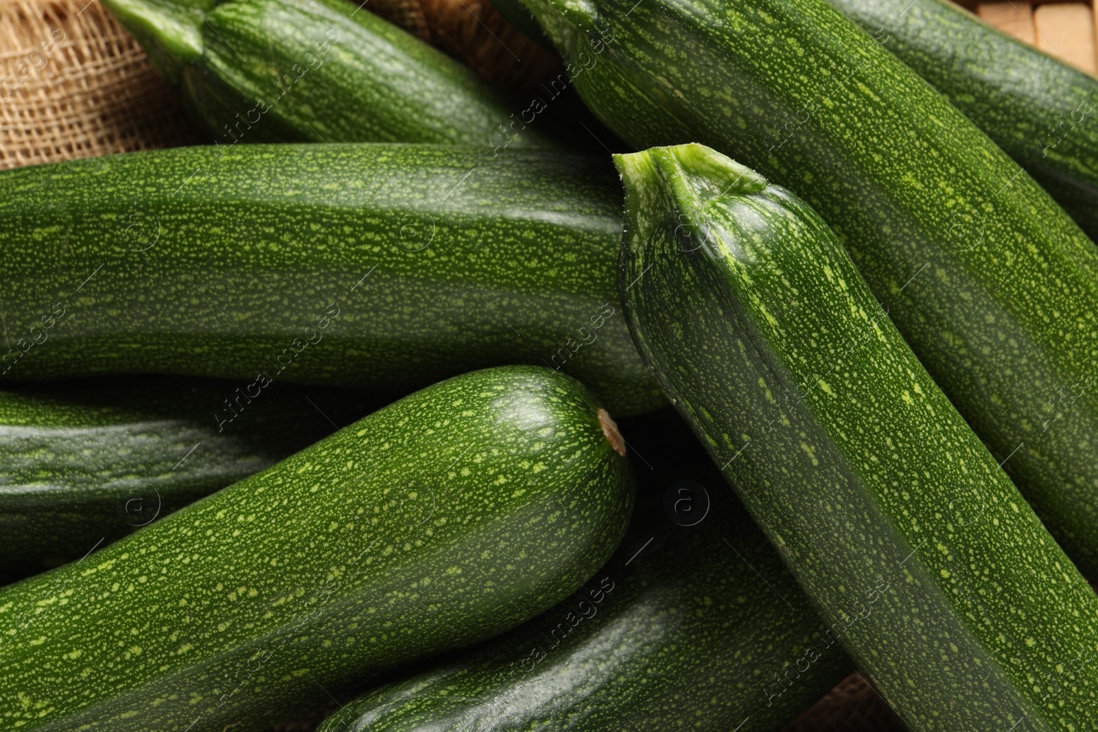 Photo of Many raw ripe zucchinis on sackcloth, closeup