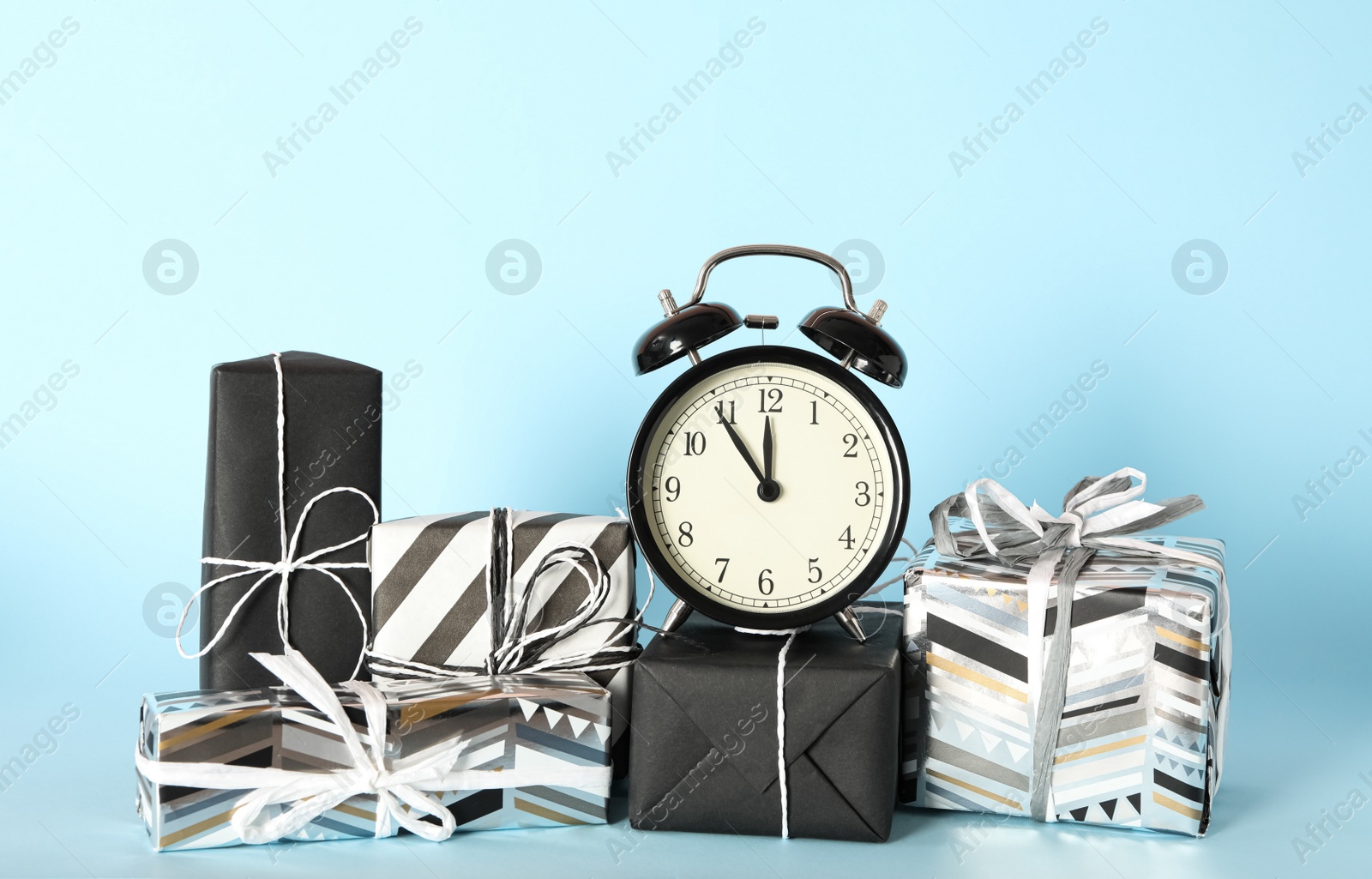 Photo of Vintage alarm clock with Christmas decor on light blue background. New Year countdown