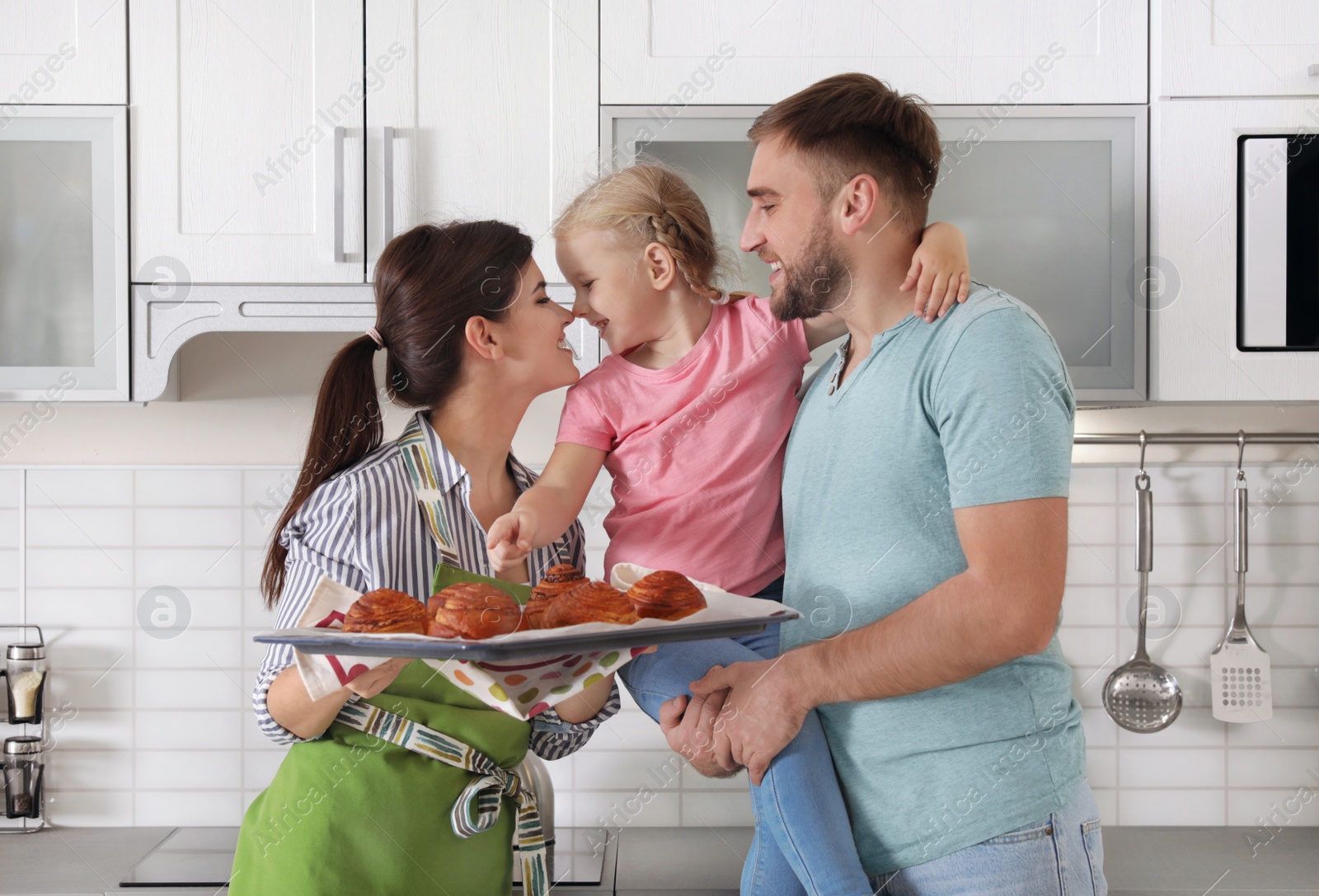 Photo of Beautiful woman treating her family with freshly oven baked buns in kitchen