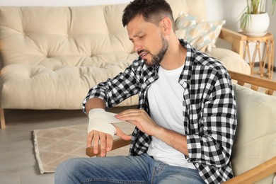 Man applying medical bandage onto hand at home