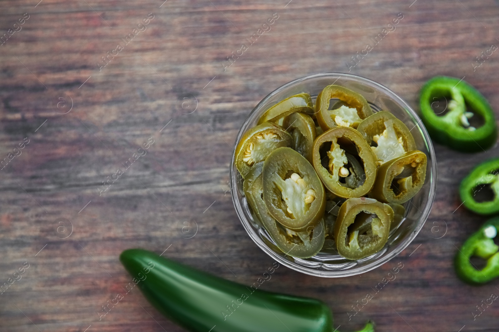 Photo of Fresh and pickled green jalapeno peppers on wooden table, flat lay. Space for text