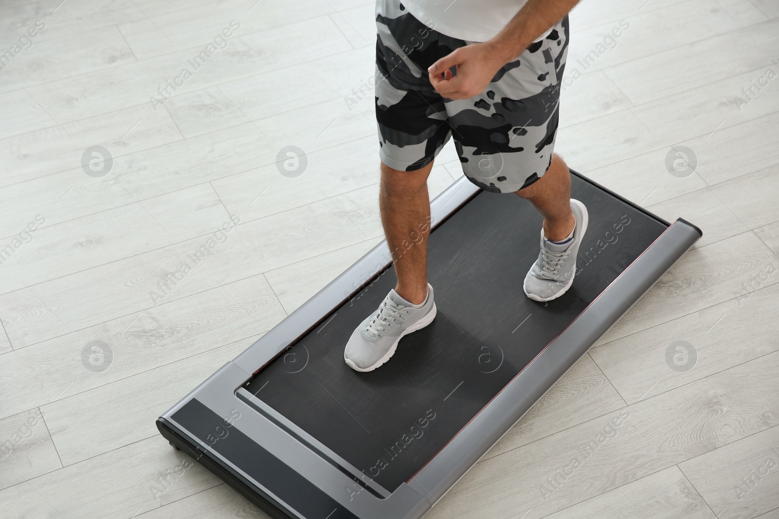 Photo of Sporty man training on walking treadmill at home, closeup