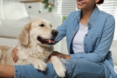 Young woman and her Golden Retriever at home, closeup. Adorable pet