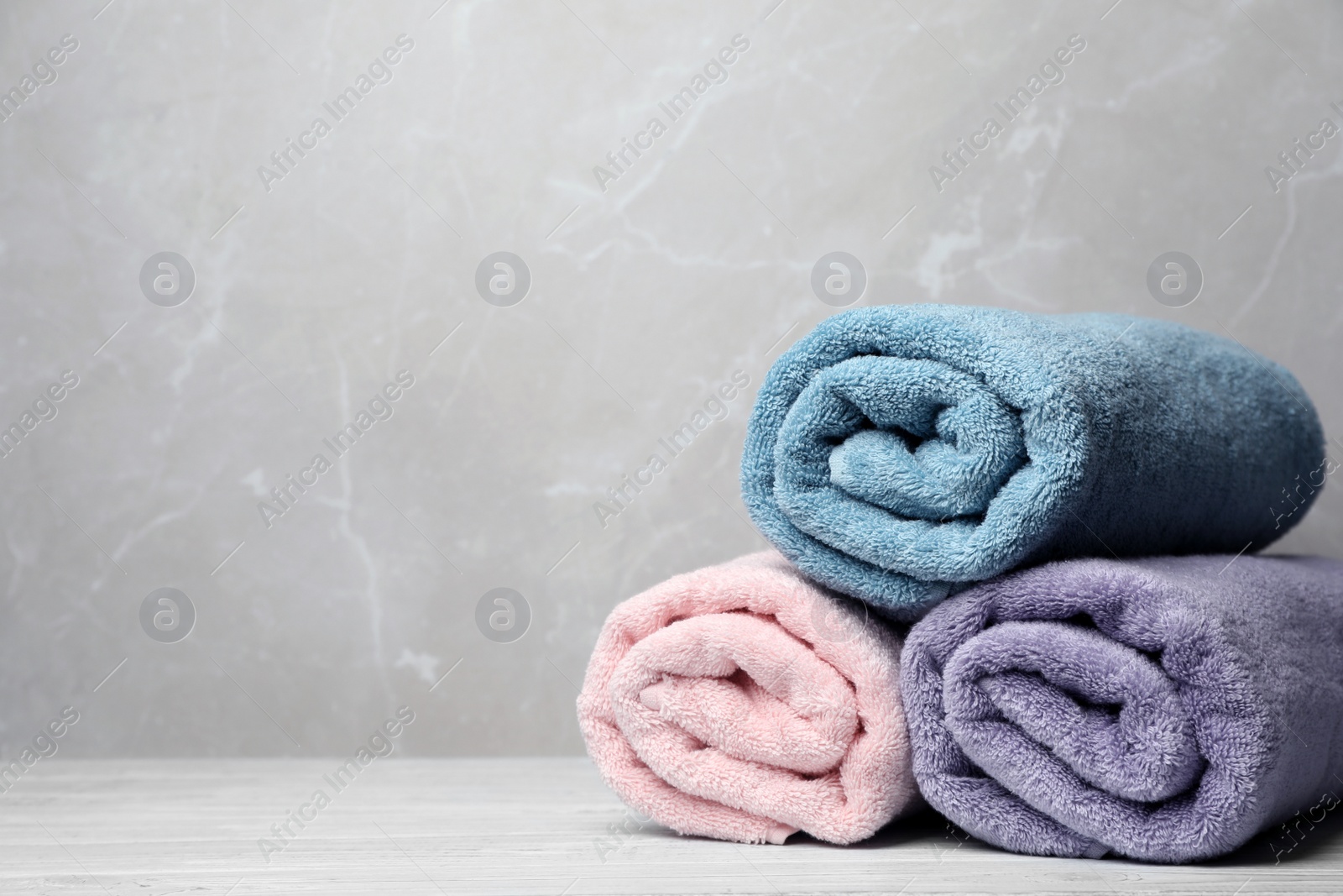 Photo of Pile of fresh rolled towels on table. Space for text