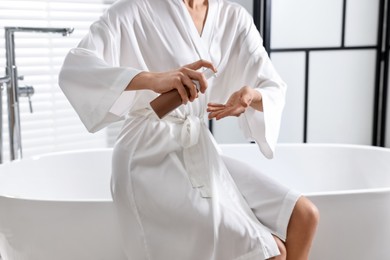 Photo of Woman applying self-tanning product onto hand in bathroom, closeup