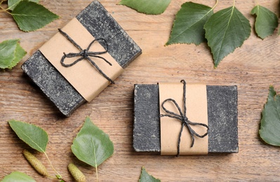 Natural tar soap on wooden table, flat lay