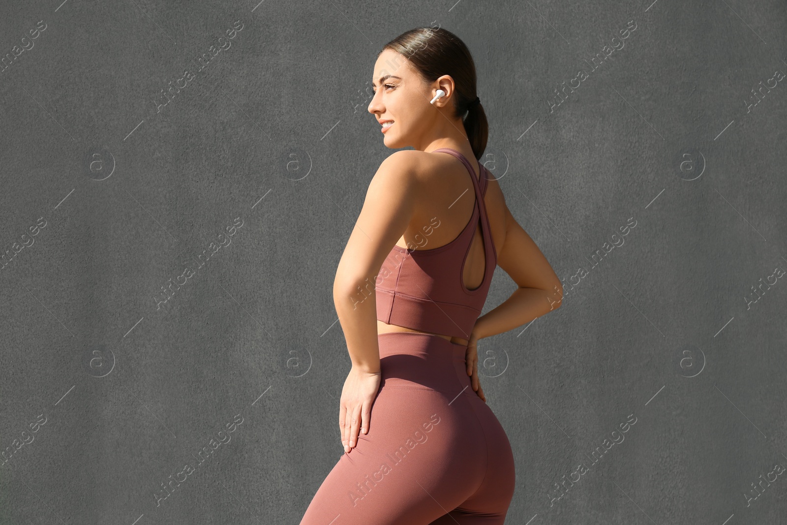 Photo of Young woman in stylish sports wear on grey background
