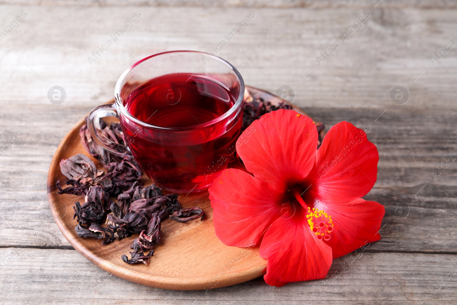 Photo of Delicious hibiscus tea and flowers on wooden table, closeup