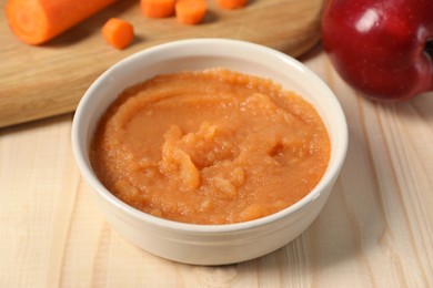 Photo of Healthy baby food. Bowl with delicious carrot puree on wooden table, closeup