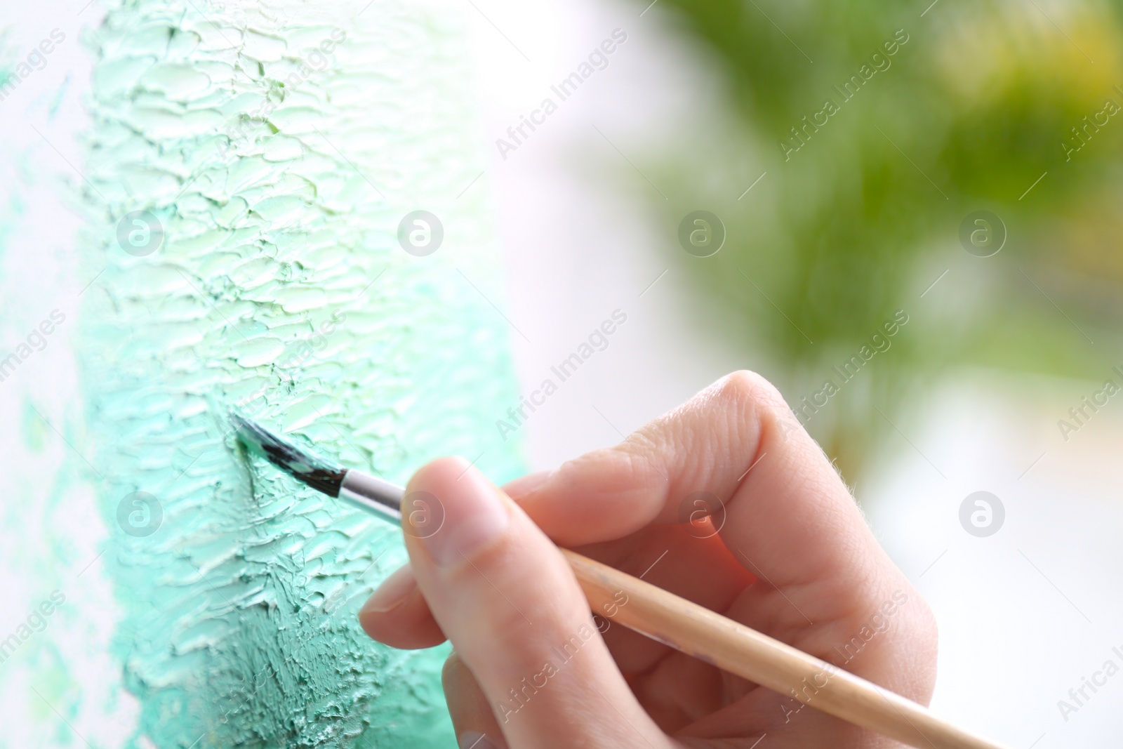 Photo of Artist painting on canvas with brush, closeup