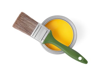 Photo of Can with yellow paint and brush on white background, top view