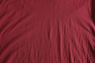 Photo of Crumpled dark red fabric as background, top view