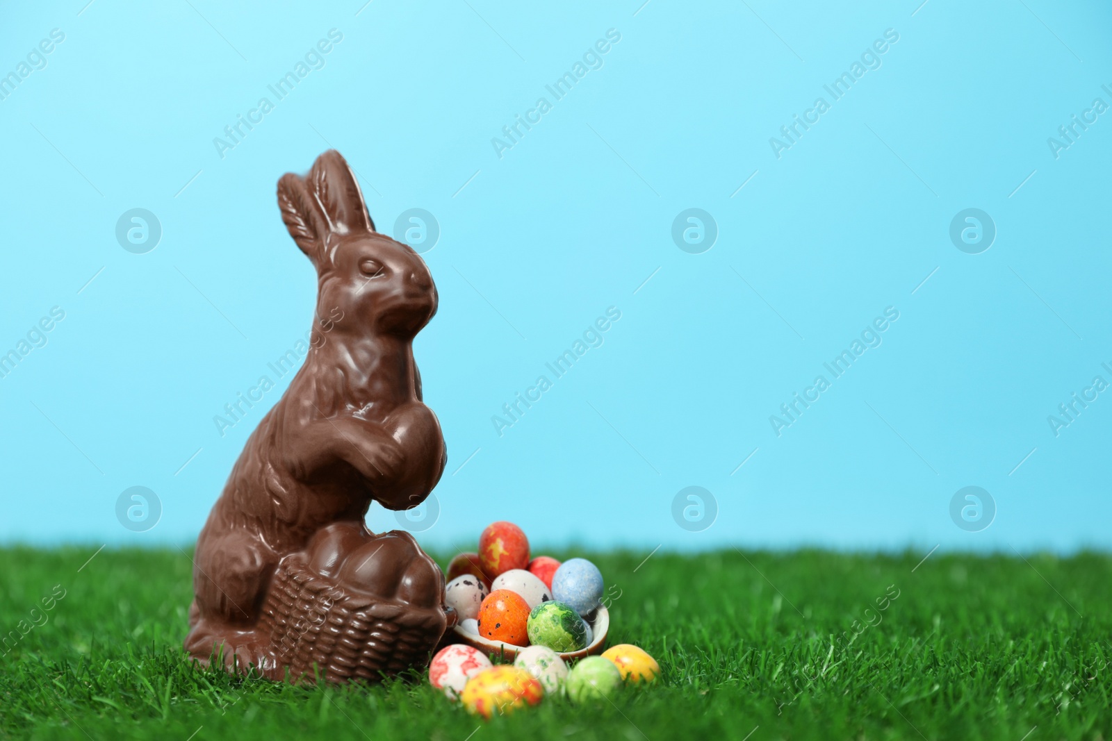 Photo of Chocolate Easter bunny and eggs on green grass. Space for text