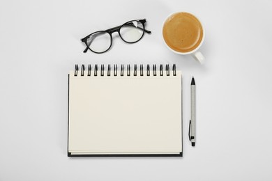 Photo of Open notebook, coffee, pen and glasses on table, flat lay