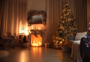 Photo of Stylish interior with beautiful Christmas tree and decorative fireplace at night
