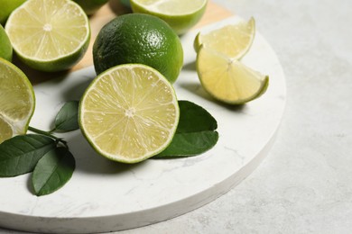 Photo of Fresh ripe limes and leaves on light table, closeup. Space for text