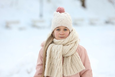 Portrait of cute little girl in snowy park on winter day