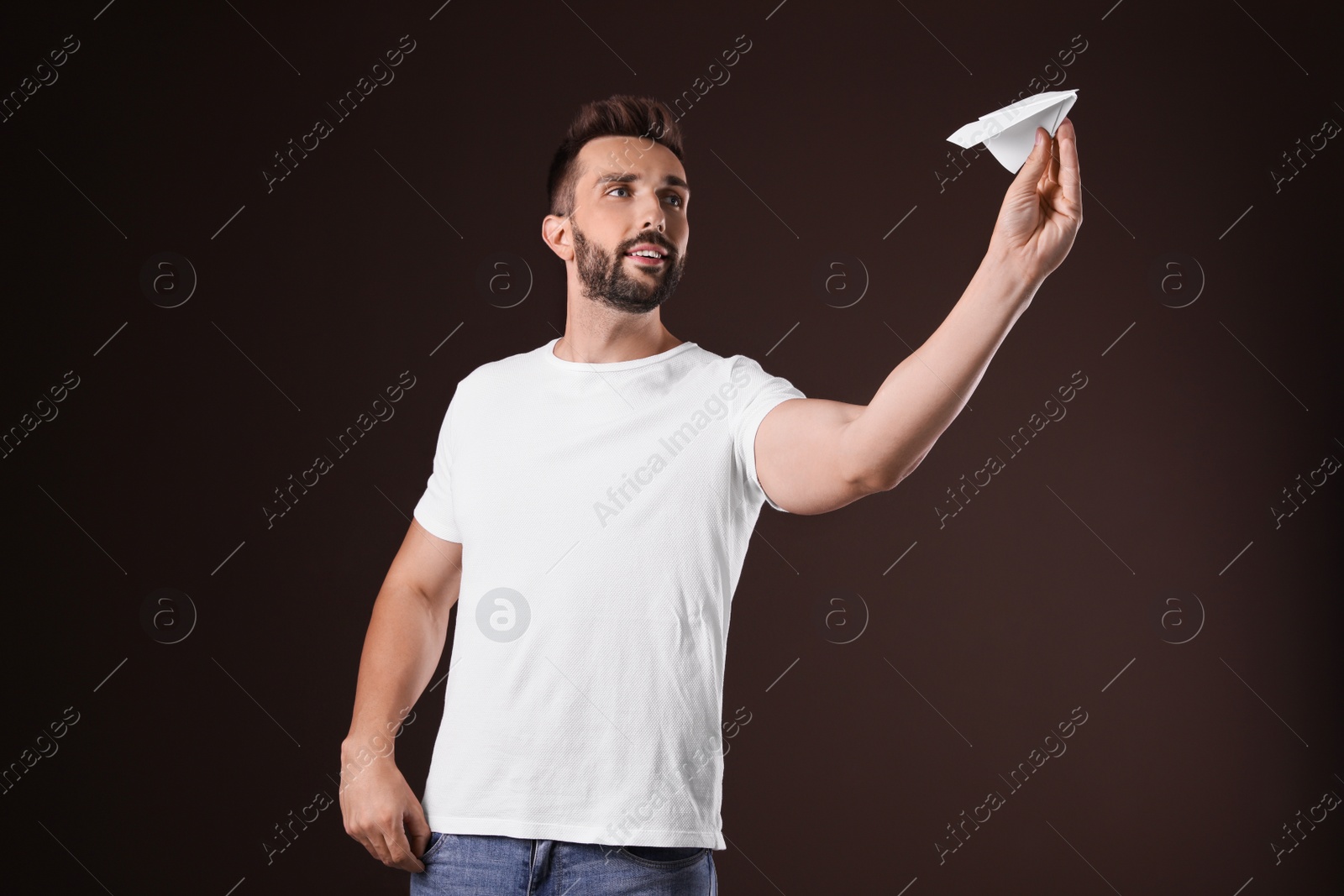 Photo of Handsome man playing with paper plane on brown background