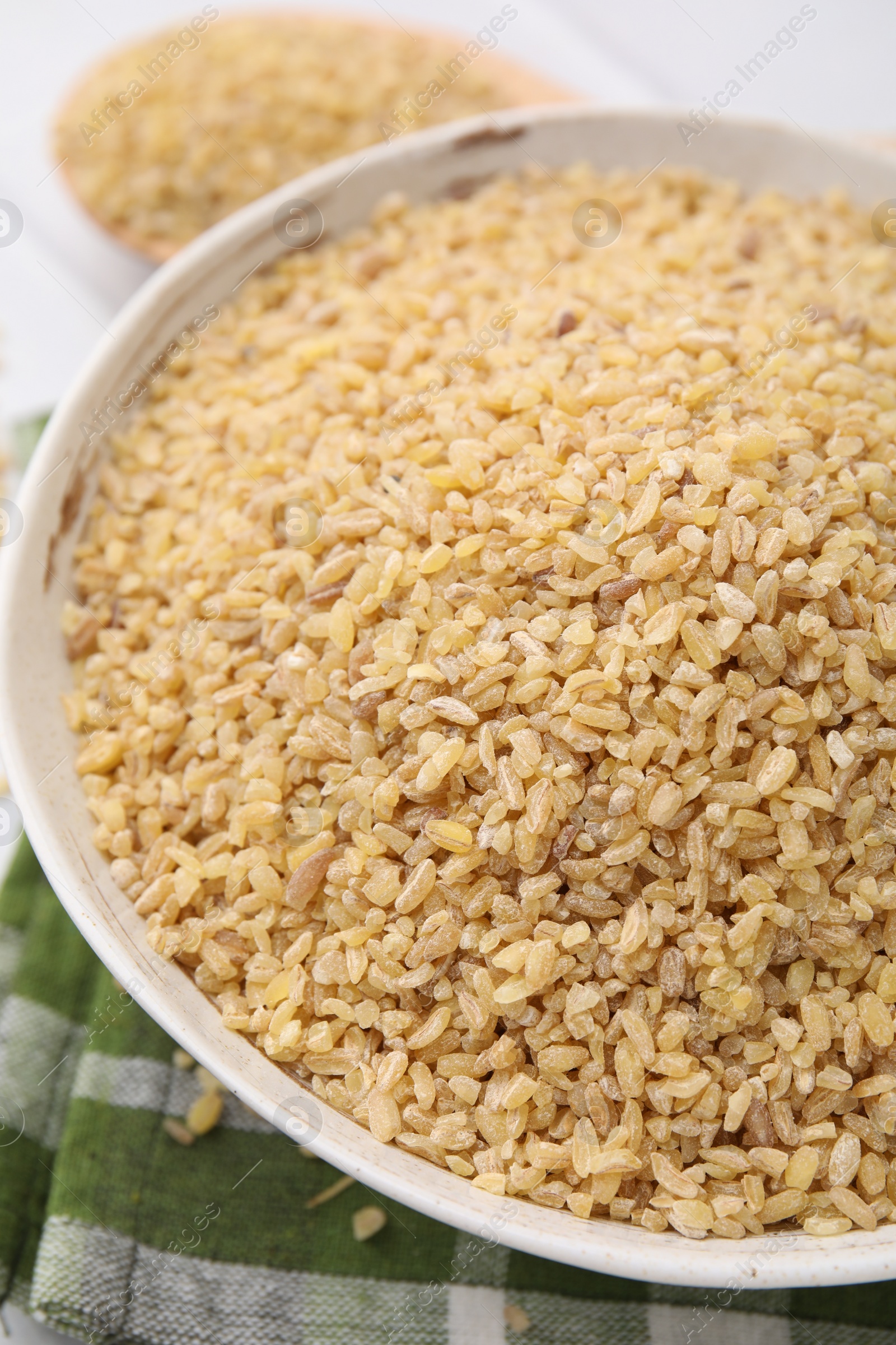 Photo of Raw bulgur in bowl on table, closeup