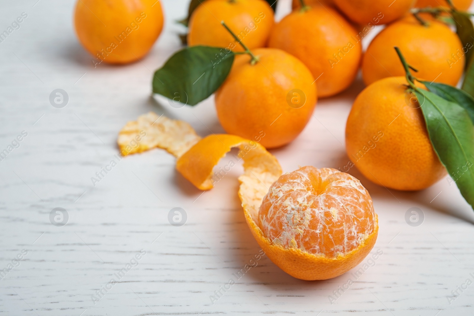 Photo of Fresh ripe tangerines with green leaves on table