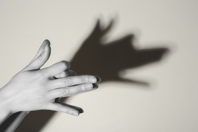 Shadow puppet. Woman making hand gesture like dog on light background, closeup. Black and white effect