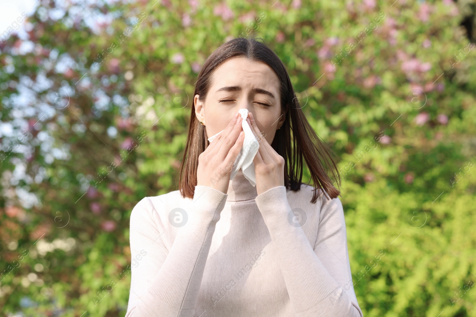 Photo of Woman with napkin suffering from seasonal allergy outdoors