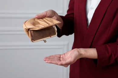 Woman with empty wallet near white wall, closeup