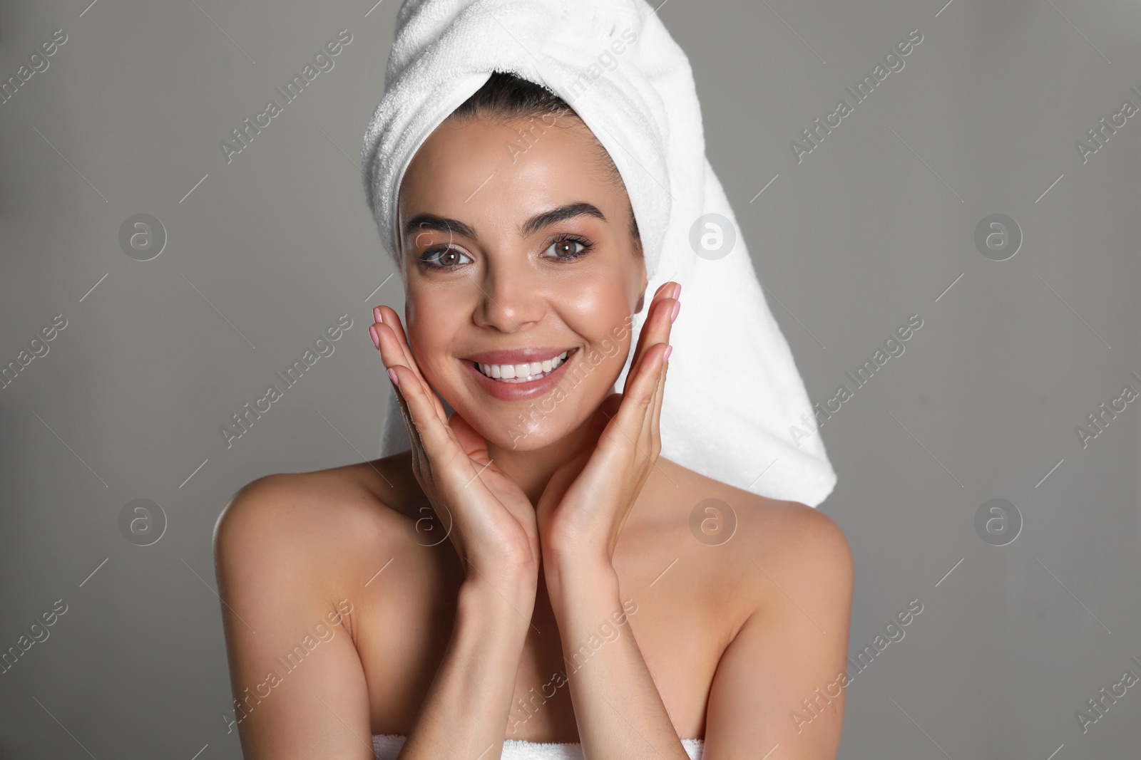 Photo of Beautiful young woman with towel on head against grey background