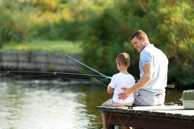 Dad and son fishing together on sunny day. Space for text