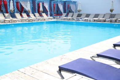 Photo of Outdoor swimming pool with sunbeds at resort on sunny day