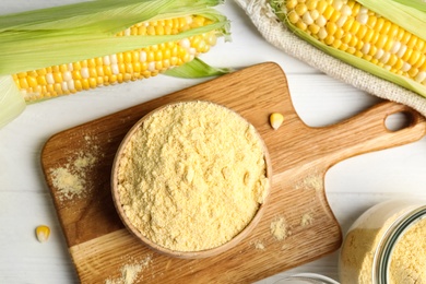 Photo of Corn flour in bowl on white wooden table, flat lay