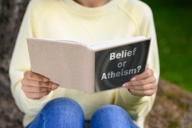 Image of Woman reading book about belief and atheism outdoors, closeup