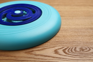 Photo of Blue plastic frisbee disk on wooden background, closeup. Space for text