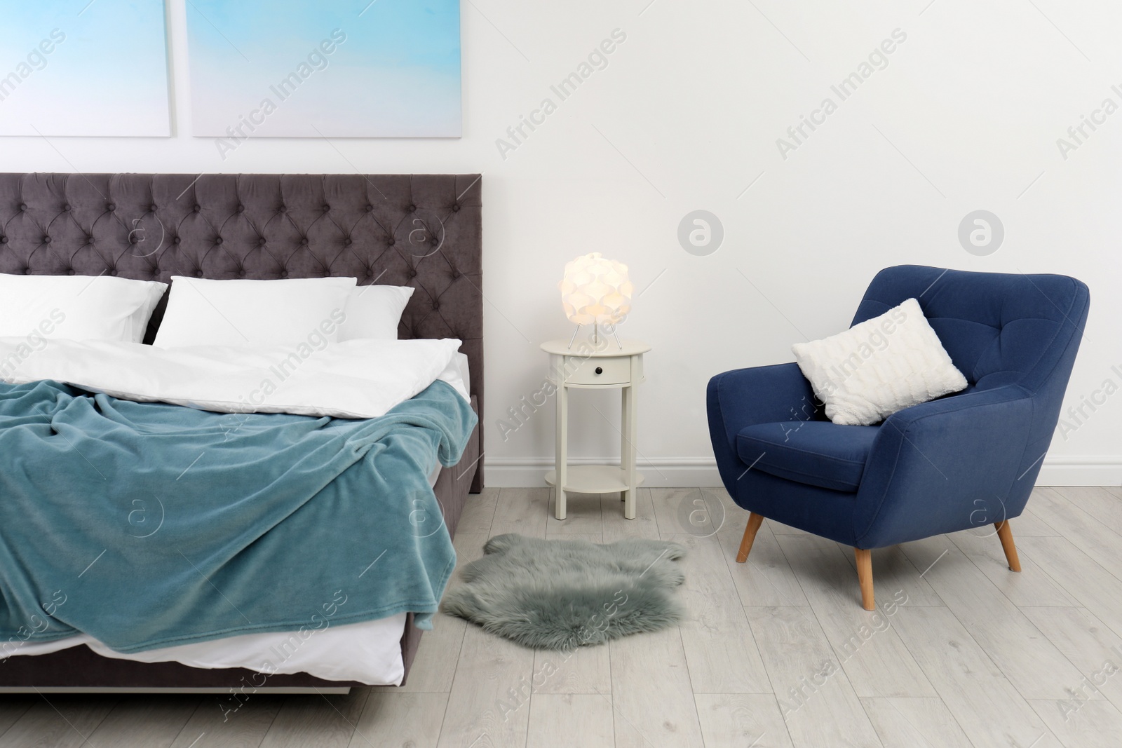 Photo of Stylish interior with comfortable double bed and armchair