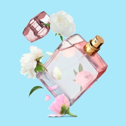 Bottle of perfume and peonies in air on light blue background. Flower fragrance