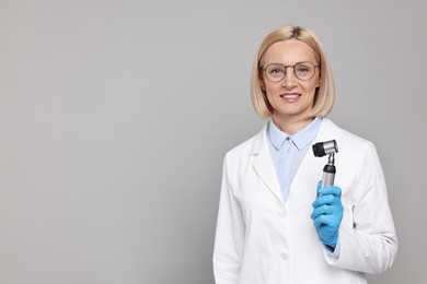 Photo of Happy dermatologist with dermatoscope on grey background, space for text