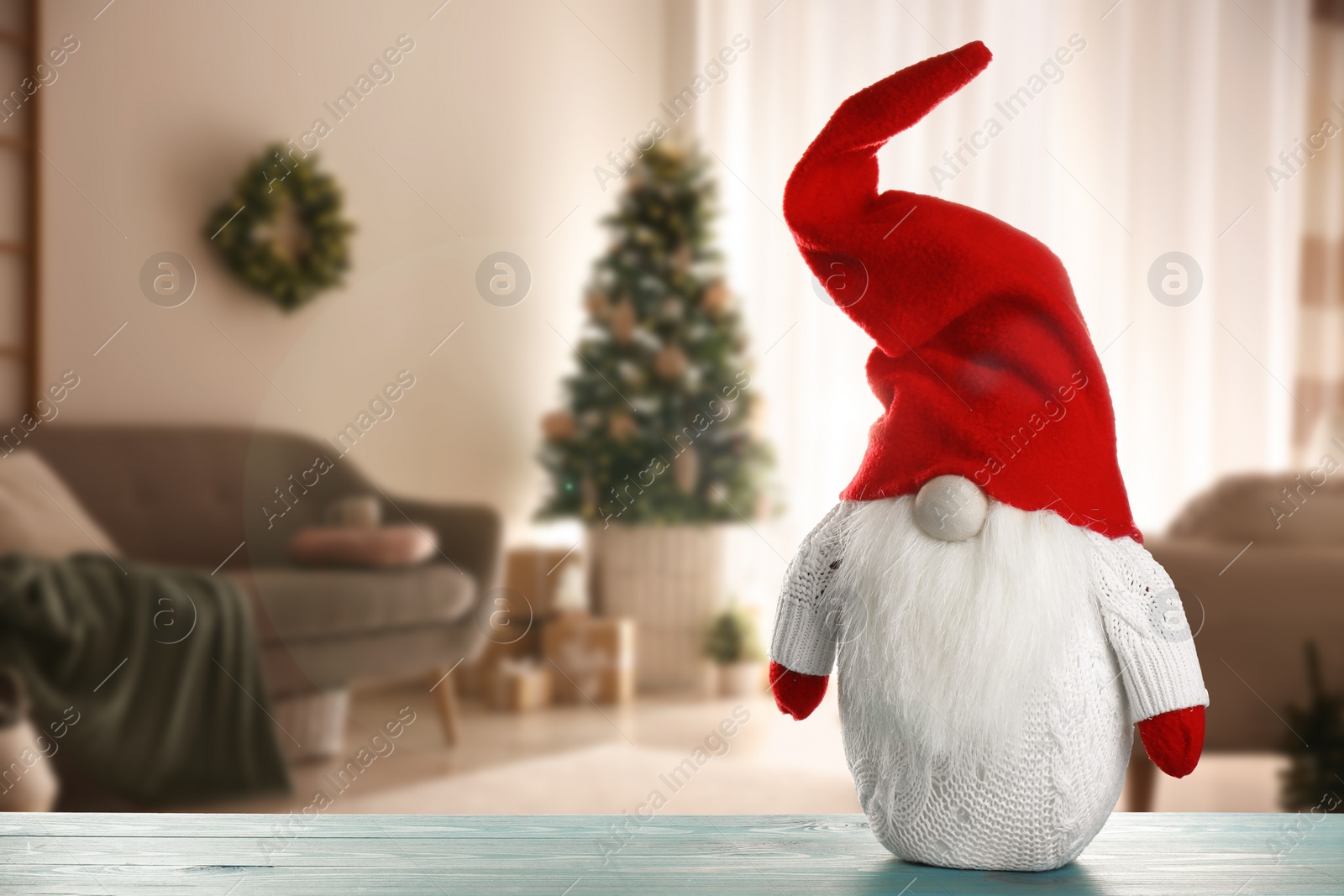 Image of Funny Christmas gnome on turquoise wooden table in room with festive decorations. Space for text