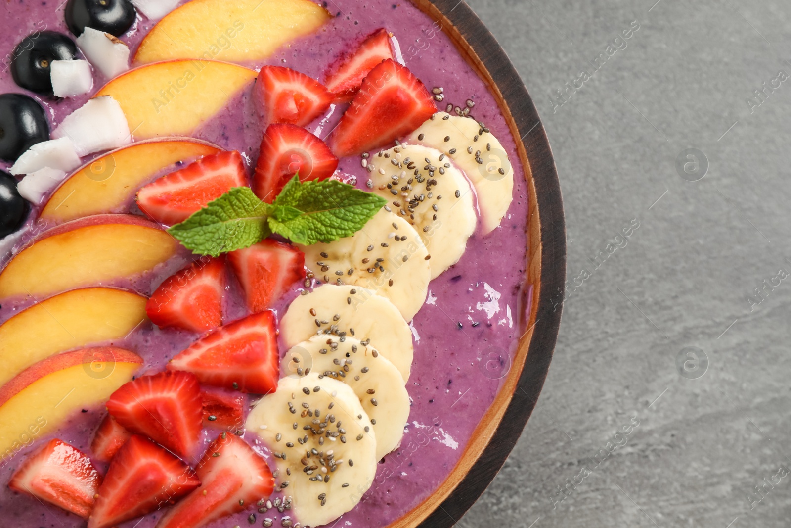 Photo of Delicious acai smoothie with fresh fruits on grey table, top view