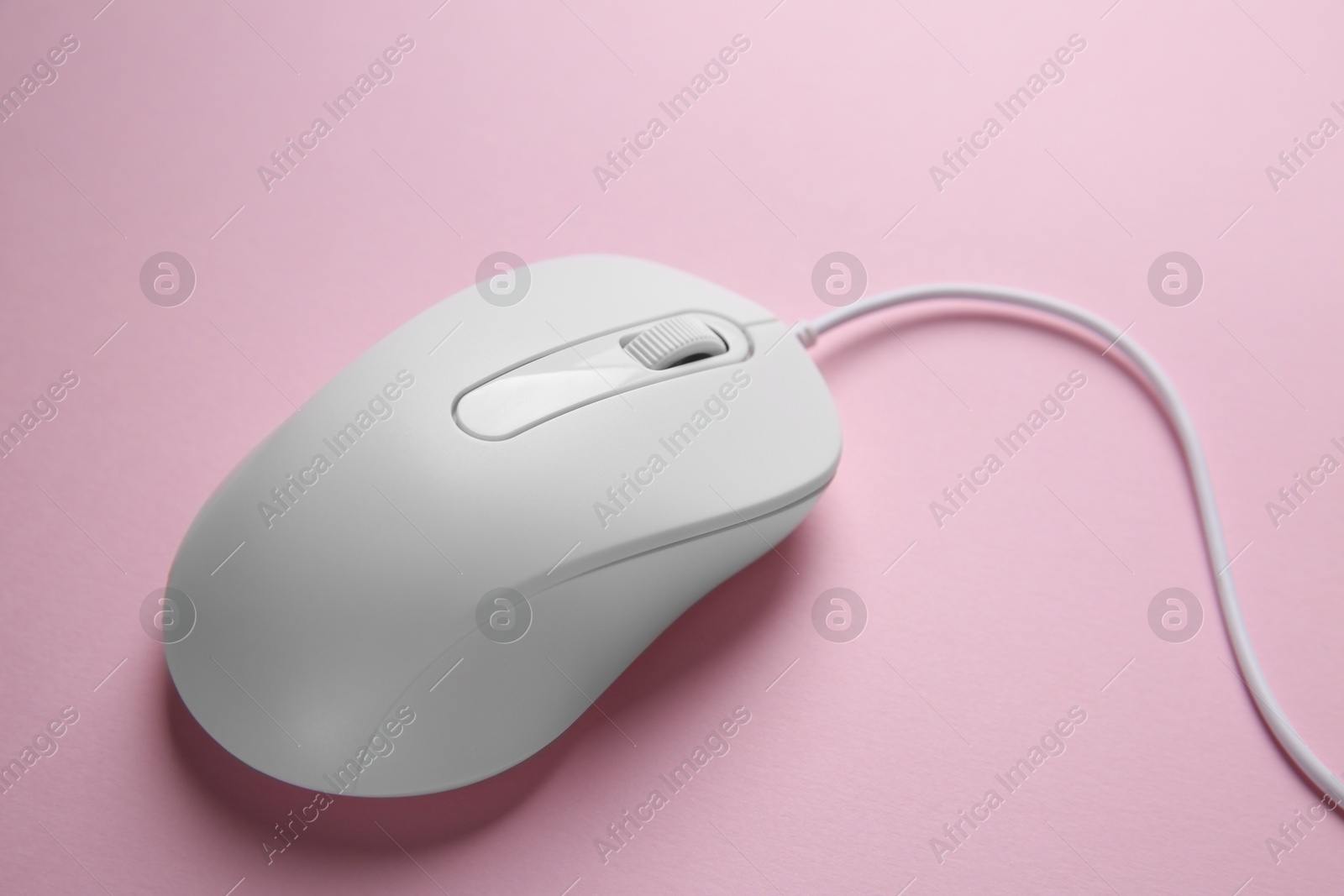 Photo of One wired mouse on pink background, closeup