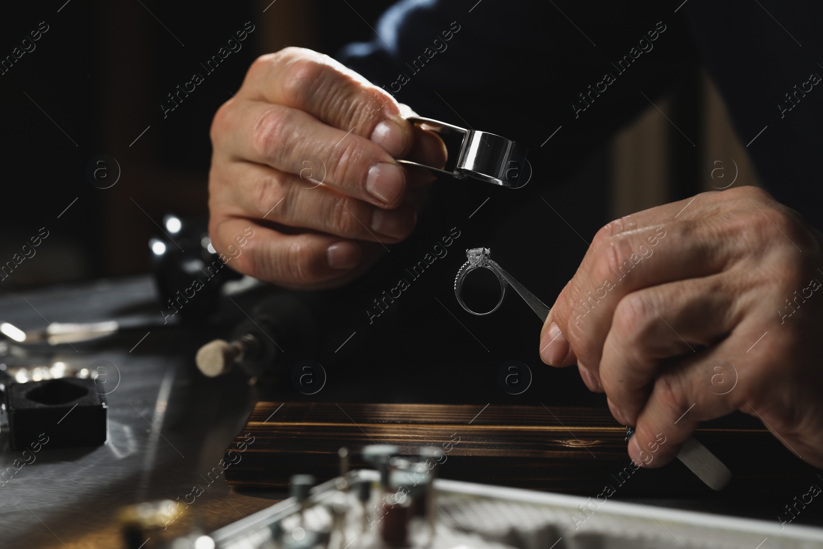 Photo of Professional jeweler working with ring at table, closeup