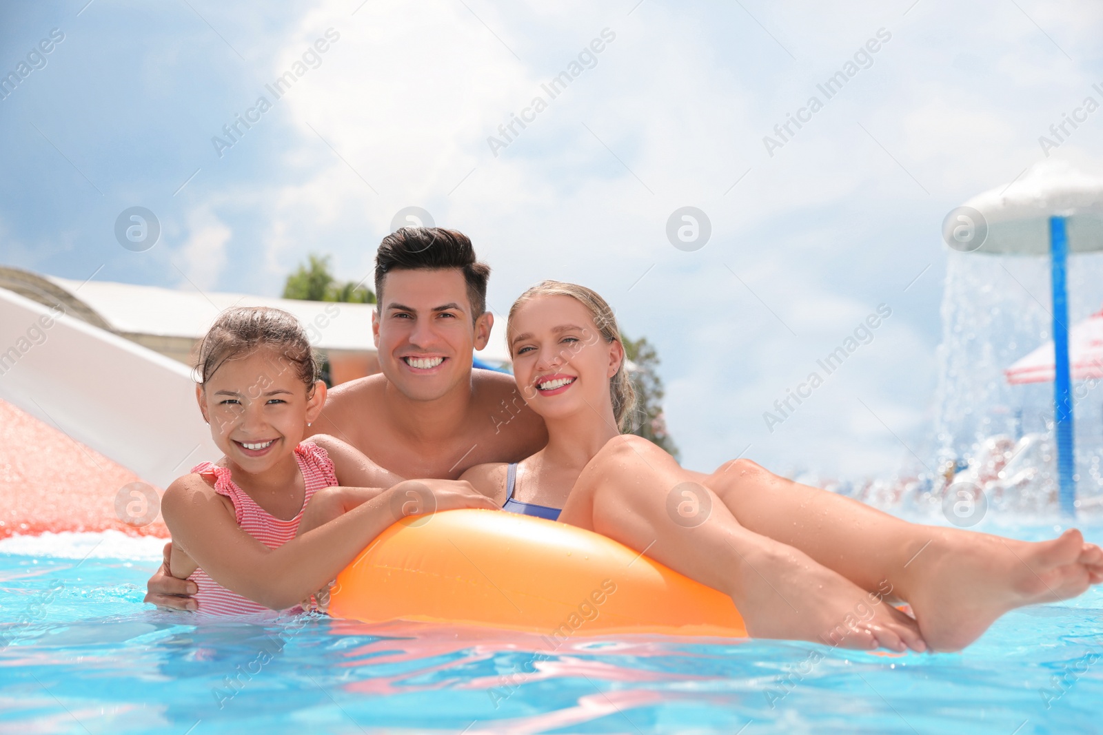 Photo of Happy family with inflatable ring in swimming pool at water park